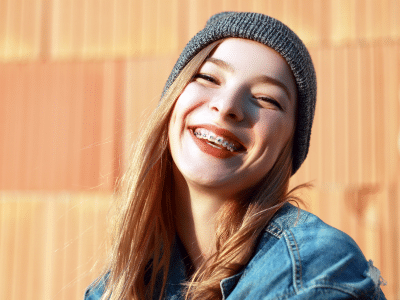 Teenage girl in beanie smiling with braces | Nudera Orthodontics