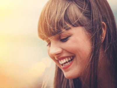 Young woman laughing and looking down | Nudera Orthodontics