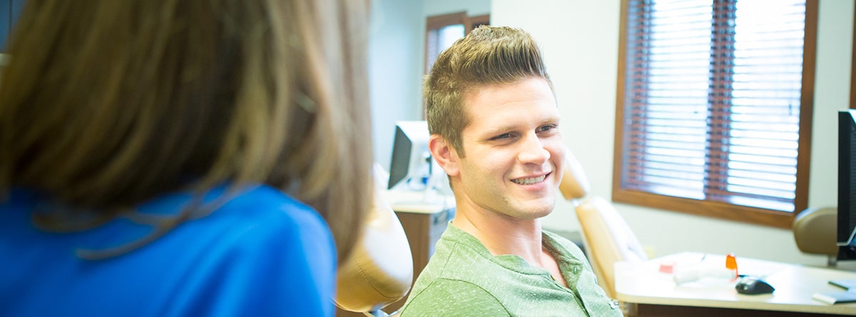 Dentist consulting with adult male patient | Nudera Orthodontics