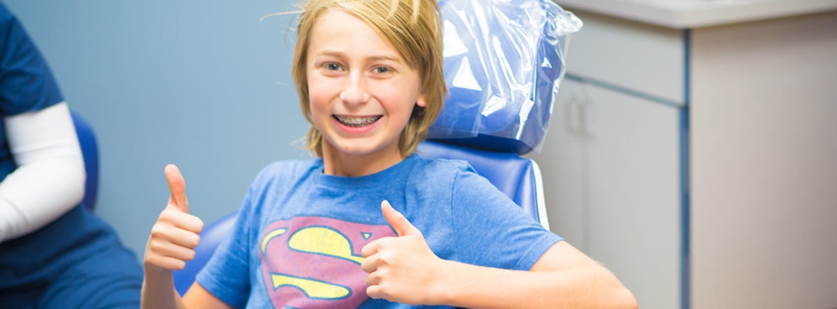 Boy in Superman shirt giving thumbs up | Nudera Orthodontics