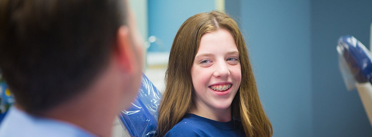 Happy young girl in blue shirt | Nudera Orthodontics