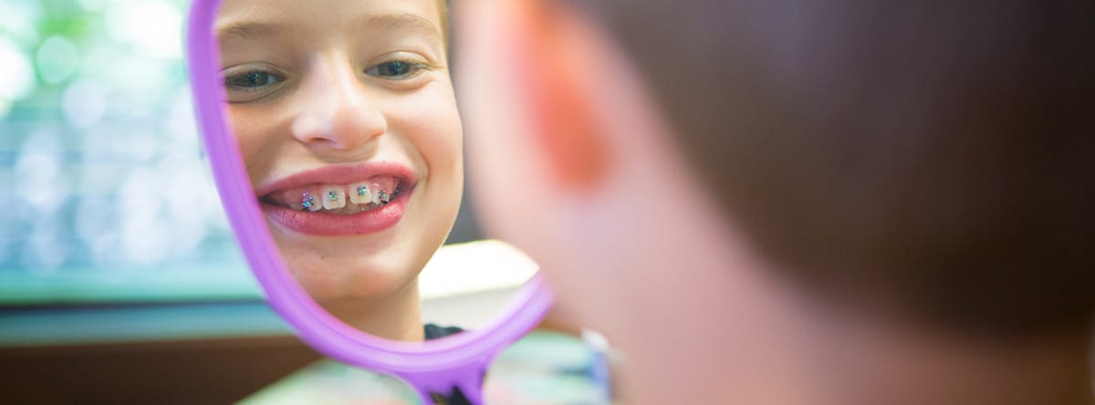 Boy looking at his braces in a mirror | Nudera Orthodontics