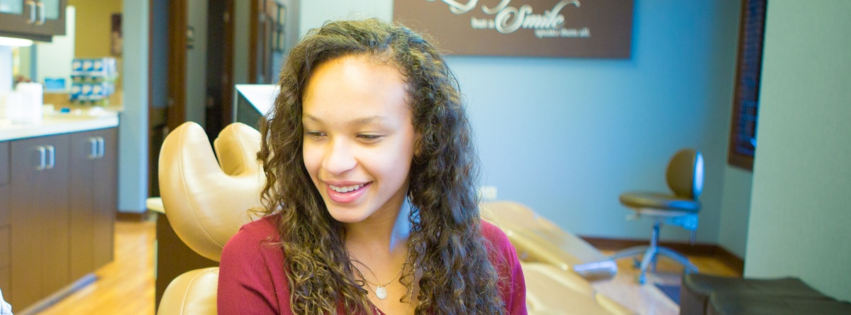Smiling girl with long brown hair | Nudera Orthodontics