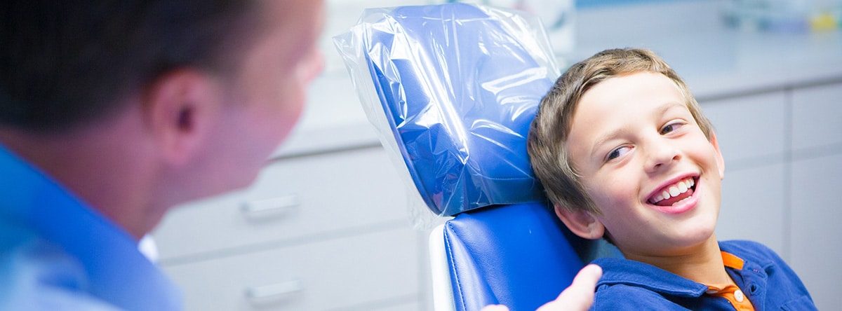 Patient reclining in blue dental chair | Nudera Orthodontics